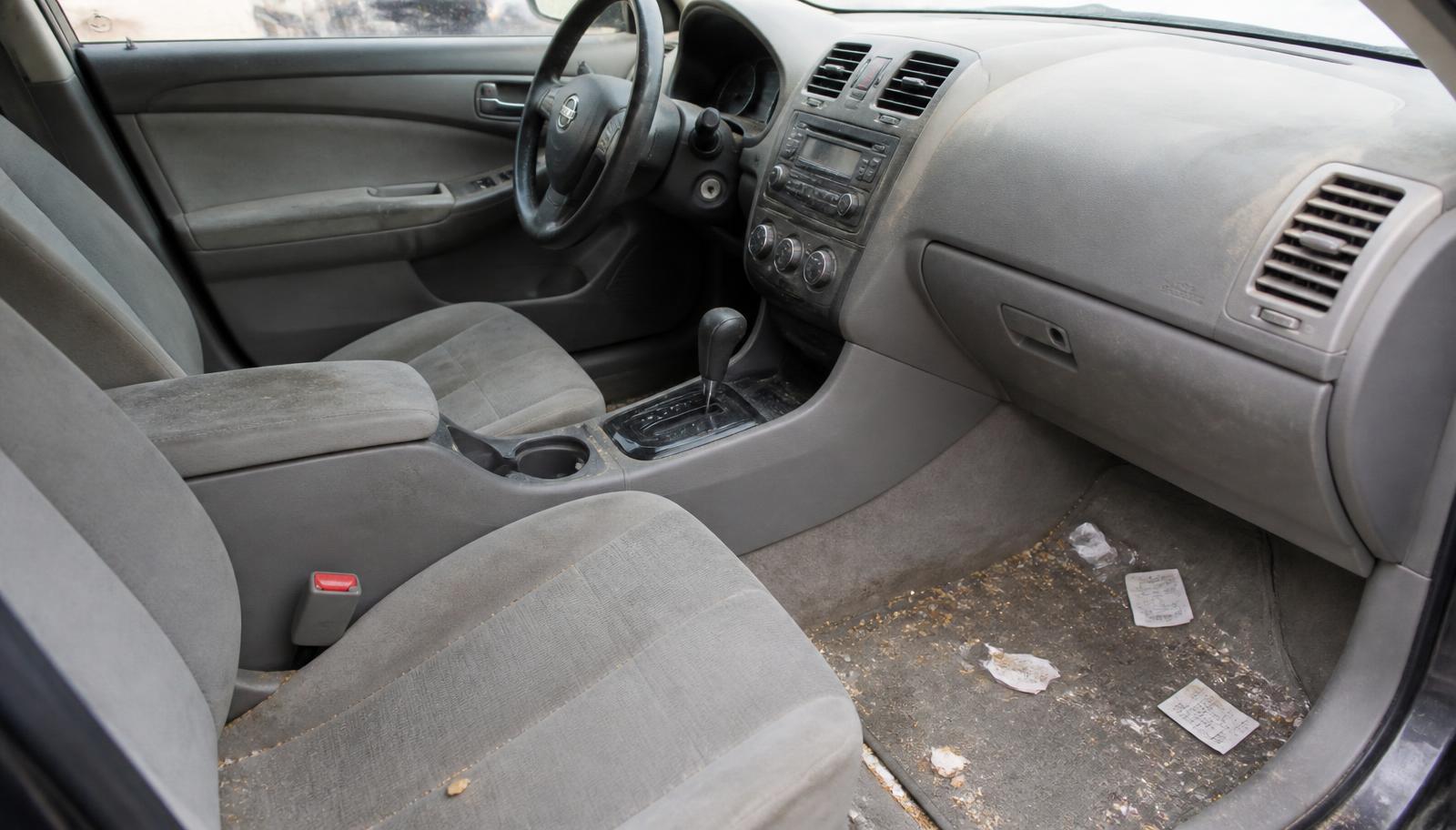 Dirty car interior with trash on the carpet before detailing